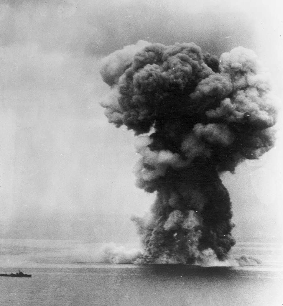 1945年4月7日,「坊之岬海战」期间,冲绳以北海域,大和号遭美国海军舰载机多次投弹及鱼雷命中后倾覆、爆炸并沉没,全舰近2500名官兵中生还者不足300人。这幅画面显示的是其沉没后不久,浓烟直冲云霄的景象。在烟雾左侧还能看见它的一艘护航驱逐舰。至此正式宣告战列舰时代在大洋上的终结。
