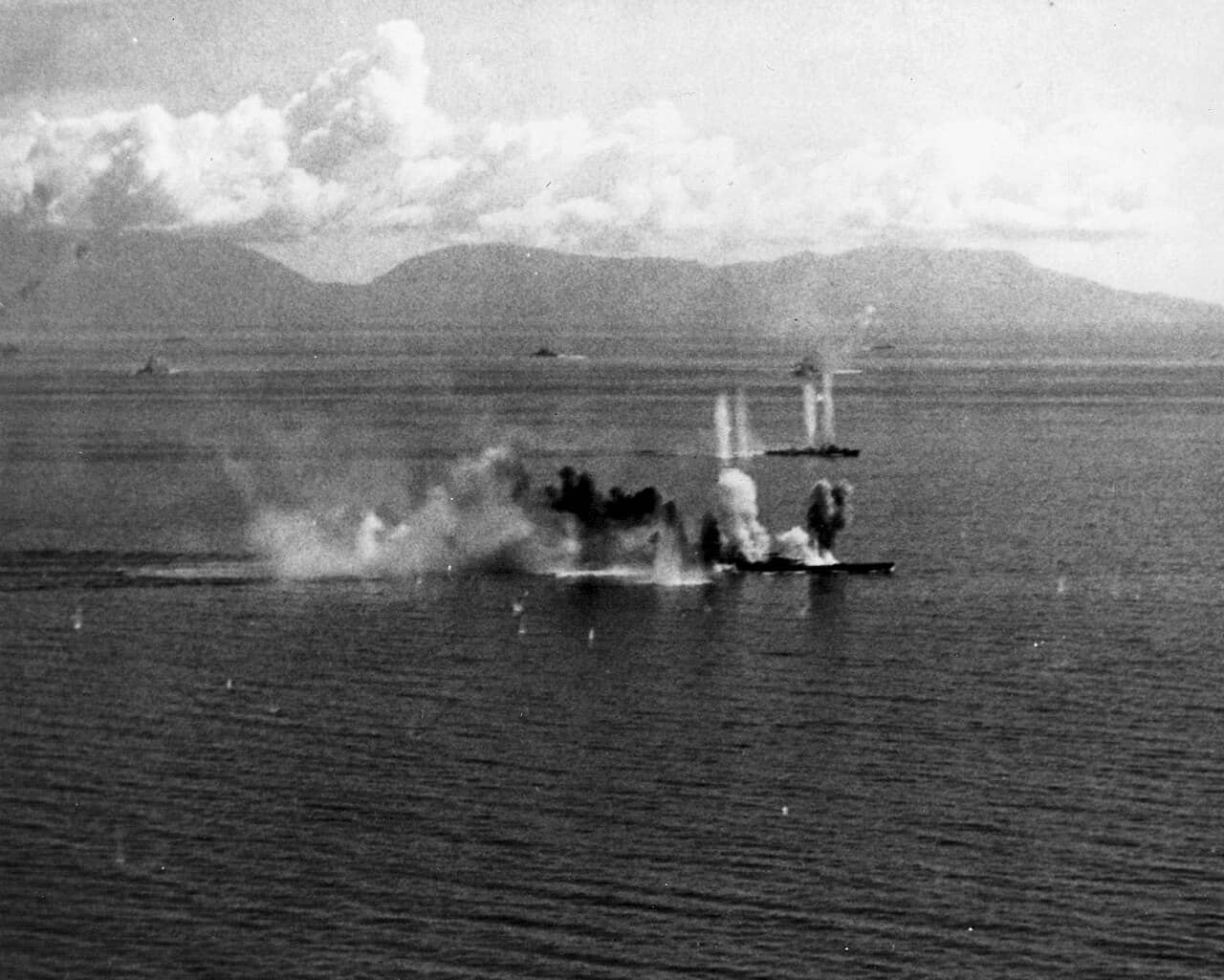 1944年10月24日「锡布延海战」中,美国海军第38特混舰队的战机在锡布延海攻击日本战列舰武藏号(近景)及一艘驱逐舰。图中可见武藏号已遭受重创,其吃水明显变浅,船身已上浮至甲板高度。而在其后方,清霜号驱逐舰也正在遭受美国军机扫射。