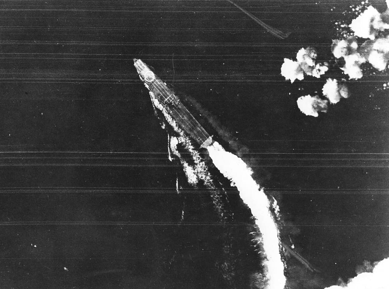 1942年6月4日,「中途岛海战」,飞龙号遭到来自中途岛沙岛(Sand Island)的B-17轰炸机攻击,照片拍摄时该舰正进行高速转弯机动以规避炸弹,注意其飞行甲板后部的「ヒ」字标识。