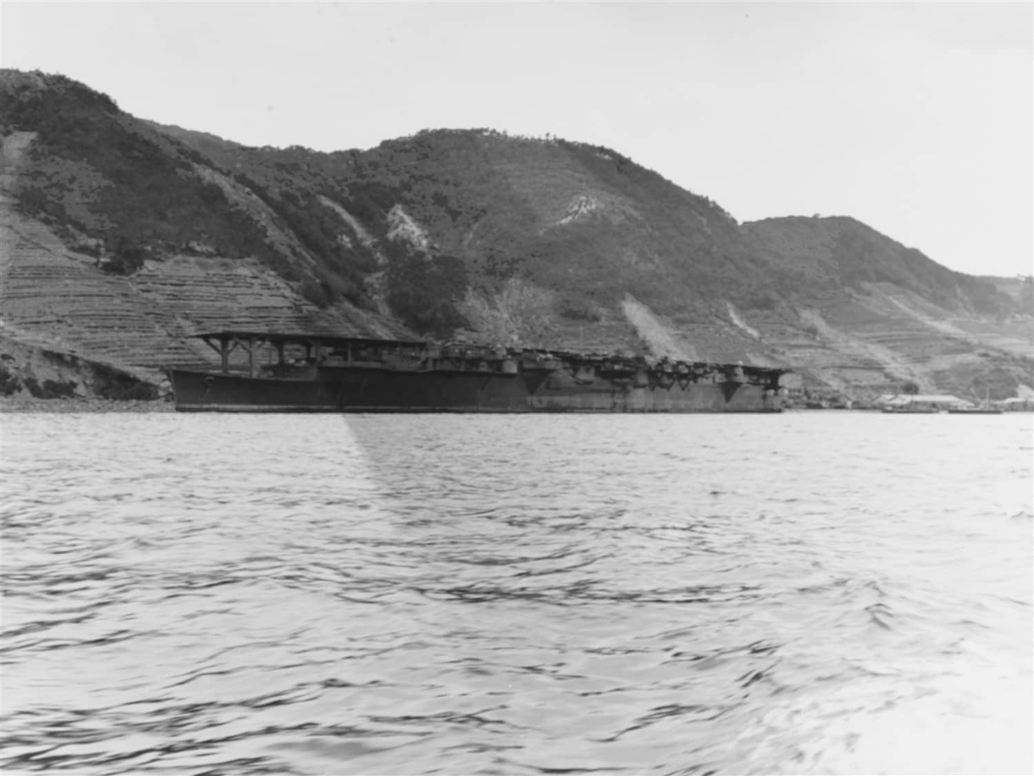 1945年10月9日,停泊于吴港的龙凤号航空母舰。此时日本已宣布投降,舰上涂装略显残旧,可见其前部飞行甲板边缘的系留设施。1945年3月19日该舰在吴港遭美军「第58特混舰队」舰载机空袭,被3枚227公斤炸弹命中后彻底报废,仅作为废船漂浮于港内直至战后解体。