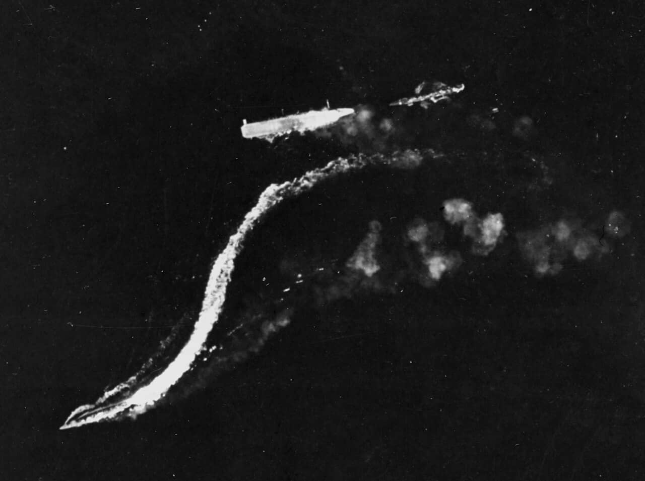 1942年8月24日，「东所罗门群岛海战」中，已被炸弹击中失去动力、舰体倾侧冒烟的龙骧号，由美军B-17轰炸机在水平轰炸中拍摄。驱逐舰天津风号（左下）与时津风号（右）正在转移舰员。当日，龙骧号在美军航母「企业」号与「萨拉托加」号航母的舰载机集中攻击下沉没。