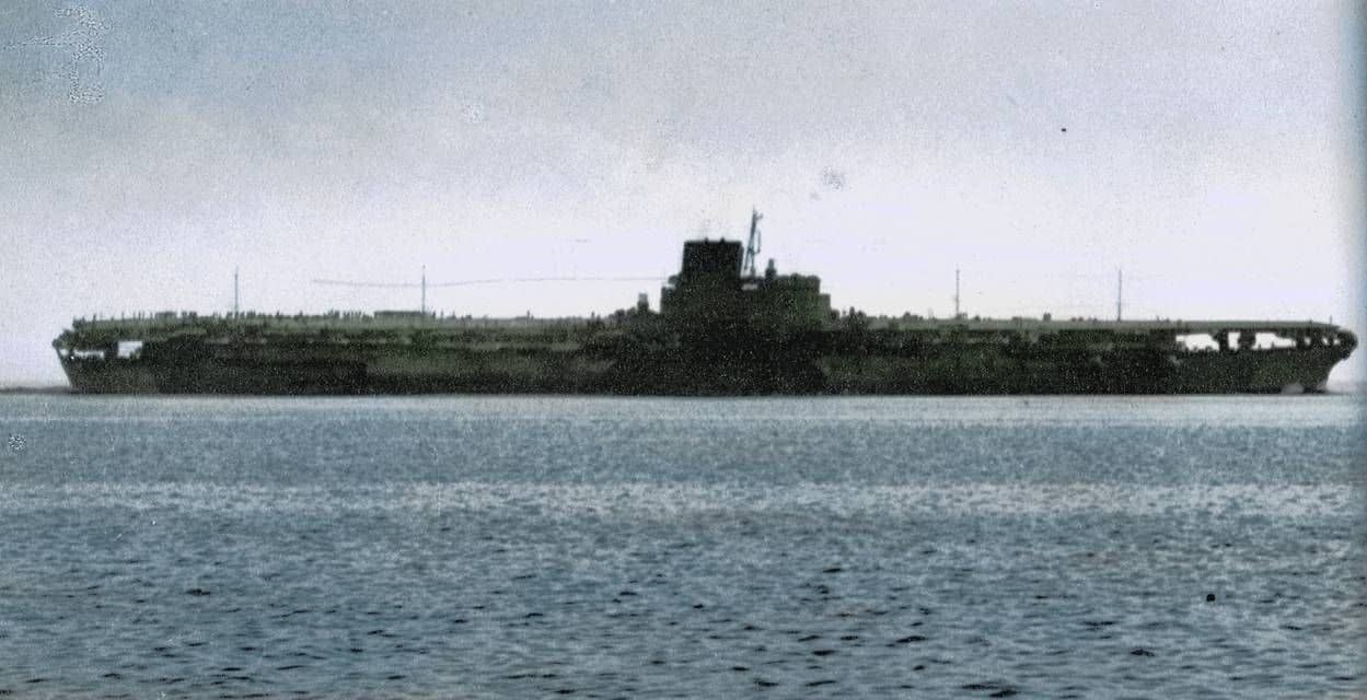 1944年11月11日，在东京湾进行海试时的信浓号。该舰由大和级战列舰三号舰在建造中途改建而成，是世界上排水量最大的航空母舰。因战局吃紧急于开赴战场，许多损管设备在舰上实际完工前并未最终安装，成为其日后处女航沉没的重要隐患。这张照片拍摄于一艘民用拖船之上。注：这张照片经过重新上色，也是后世留存下来、为数稀少的信浓号航母图片资料。