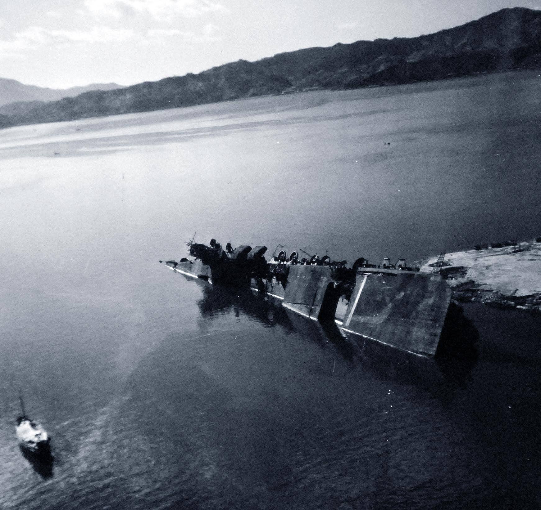 1945年10月14日,盟军占领日本期间,天城号航空母舰在吴港码头的倾覆残骸。这幅照片由隶属于「肯尼斯·惠廷」级(Kenneth Whiting-class)水上飞机母舰「圣乔治」号(USS St. George, AV-16)的美军飞机拍摄。