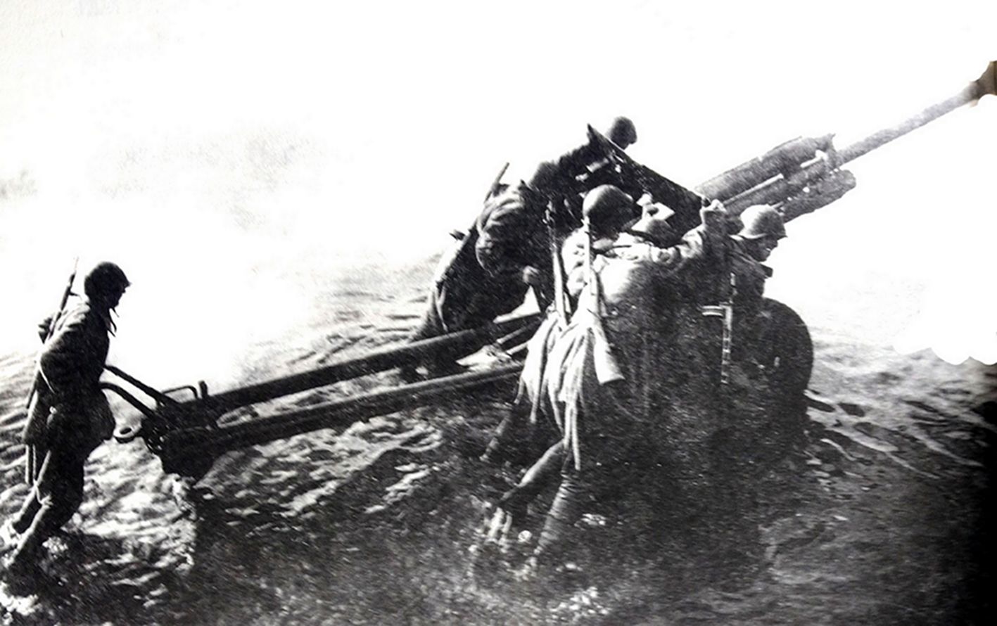 1945年4月,「柏林战役」期间,东线德国战场,苏联乌克兰第1方面军与白俄罗斯第1方面军在奥得河阵地上展开对柏林的围攻。在河滩上,炮兵们正努力推动一门1938式122毫米榴弹炮进入阵地。