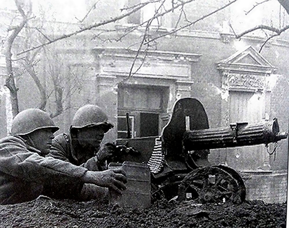 二战东线苏联战场某城内,两名苏军士兵在楼房边的重机枪阵地上,用1910/30式马克沁重机枪阻击进攻的德军。马克沁重机枪虽已落后,但在二战初期仍是苏军步兵重要火力支援武器。