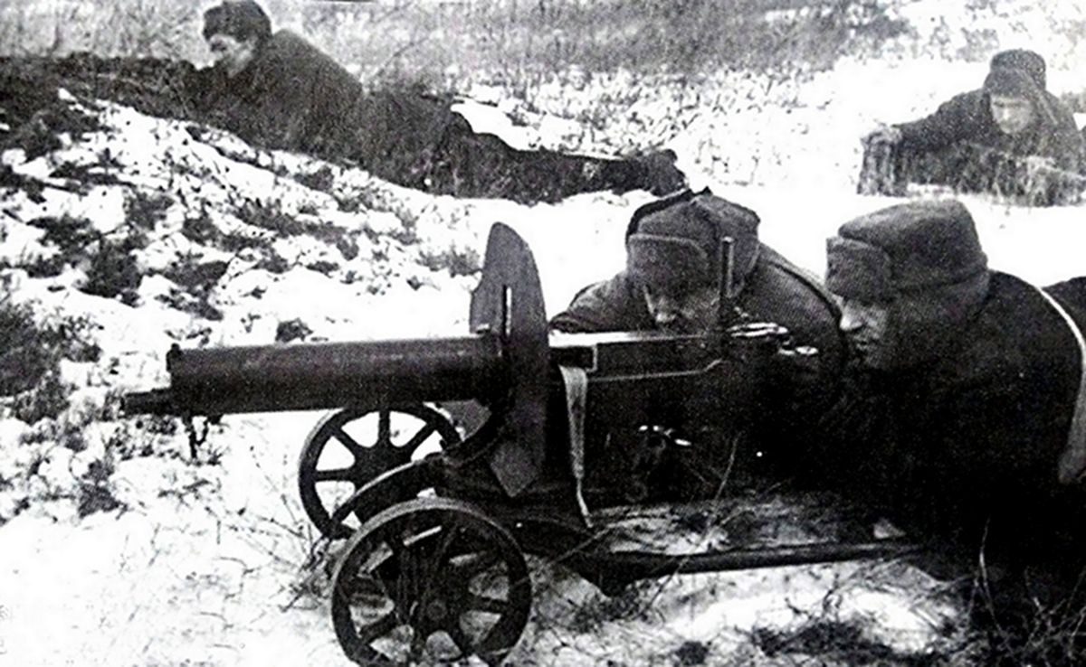二战苏联卫国战争初期,冬季寒冷雪地上,苏军一处正在战斗的1910/30式马克沁重机枪阵地,机枪手正在瞄准射击,旁边还有掩护的士兵与弹药手。