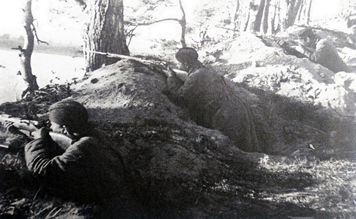1941年9月，「列宁格勒保卫战」期间，东线苏联战场列宁格勒地区，列宁格勒民兵师战士正埋伏在涅瓦河沿岸高地挖出的散兵坑阵地中，持「莫辛-纳甘」1891/30式步枪阻击进攻的德军。这些临时组建的民兵师在列宁格勒保卫战中发挥了至关重要的作用，面对德军庞大装甲集群毫不畏惧牺牲，大大减慢了德军在列宁格勒的推进速度。