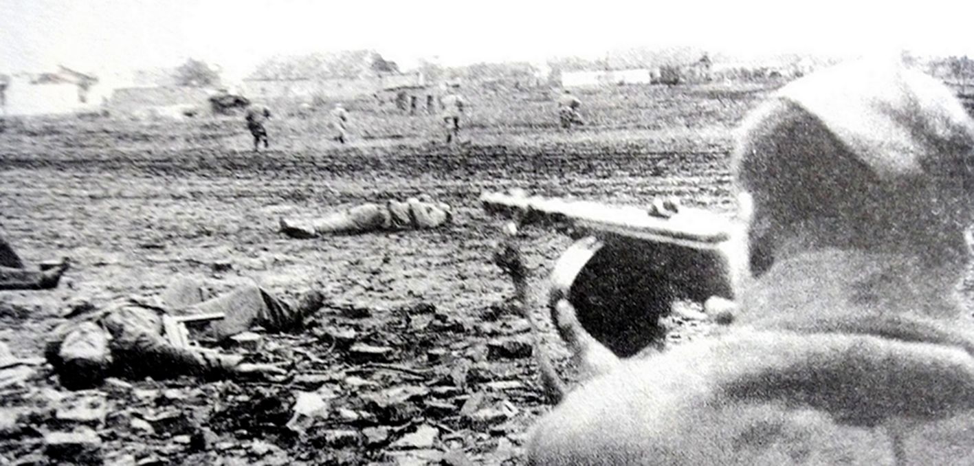 1943年秋季,东线苏联战场,一名苏军士兵用PPSh-41型冲锋枪支援冲锋的步兵,枪手近前有一些德军士兵尸体。这张照片可能是战地摄影师在战场上临时要求这位冲锋枪手摆拍的,因为PPSh-41型冲锋枪有效射程只有150米,无法对前方冲锋的士兵作如此远距离火力支援;这些德军士兵尸体也可能不是在照片位置战死的。但照片却真实反映了战场的残酷。