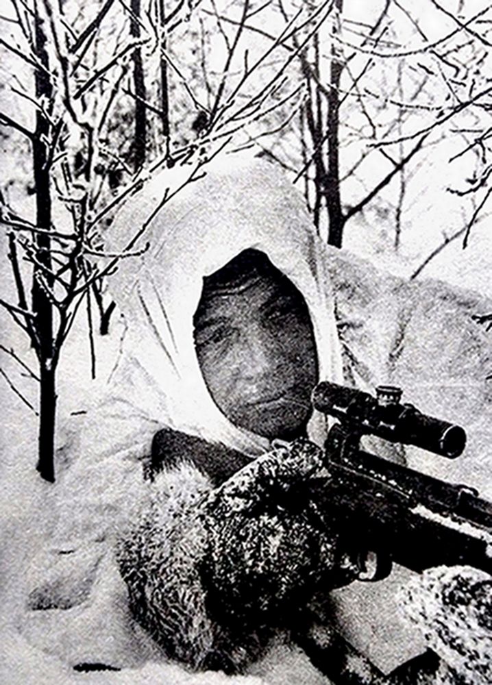 二战东线苏联战场,一名手持SVT-40半自动步枪、埋伏在树丛雪地中的苏军狙击手。为了方便扣扳机,他戴的防寒皮手套专门留有一个手指孔。