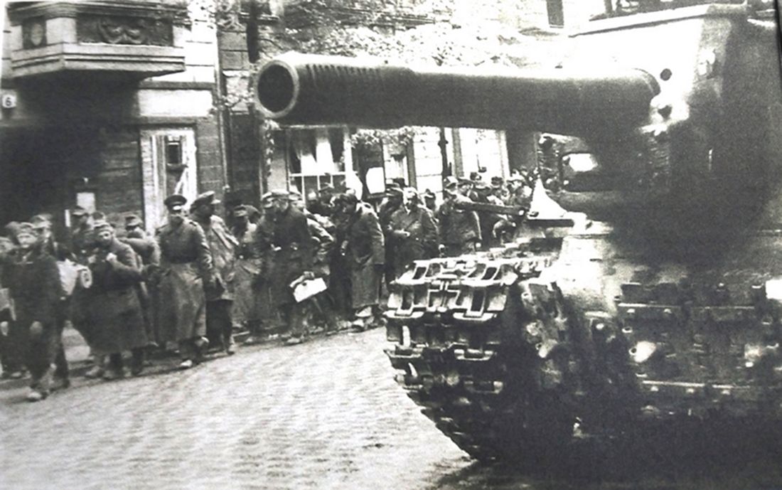 1945年5月,「柏林战役」期间,德国柏林大街上的一辆苏军ISU-152型自行突击炮车,炮车旁是一队德军战俘。