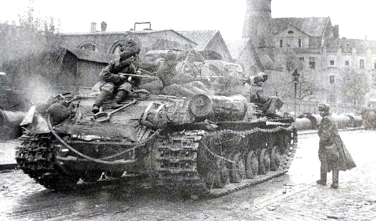 1945年5月，「柏林战役」期间，一辆IS-2重型坦克在一名苏军军官指挥下驶过柏林大街，坦克上坐着一群苏军步兵。