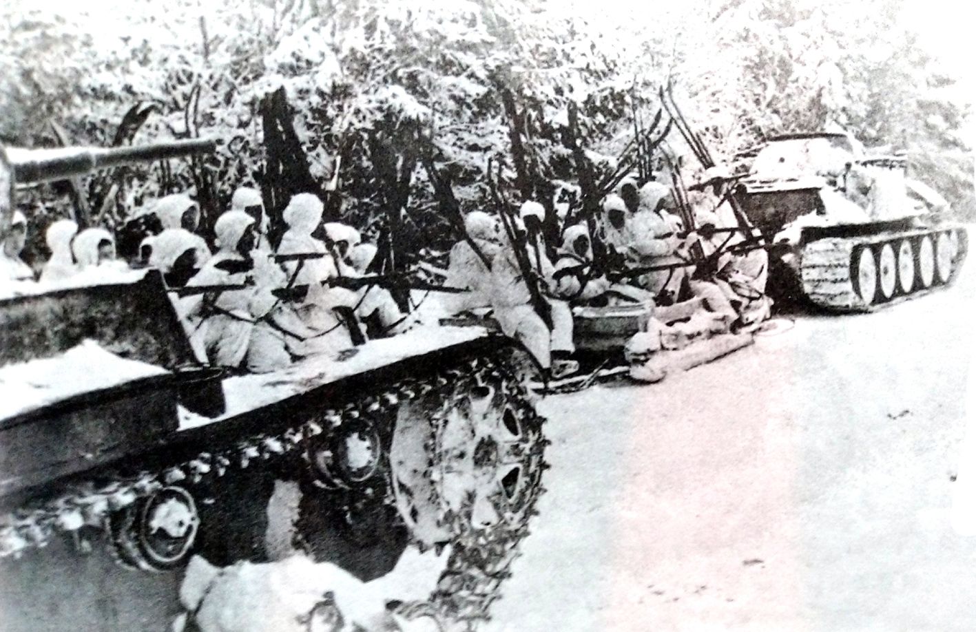 苏军一辆T-26轻型坦克（士兵后面）和一辆T-34中型坦克（士兵前面）在为一批滑雪士兵作行进掩护，准备进行反攻。