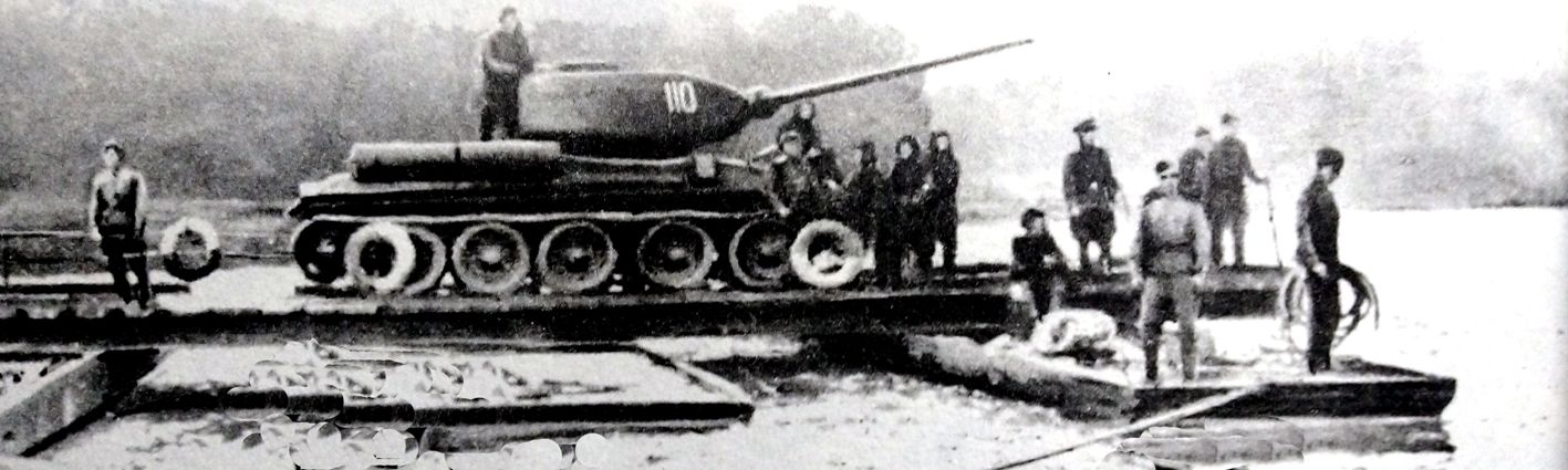 1943年，「库尔斯克会战」期间，东线苏联战场，在哈尔科夫地区伊祖姆镇附近，一辆苏军T-34/85坦克正搭乘木筏准备渡过北顿涅茨河。