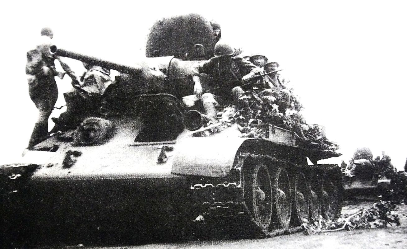 1943年7月，「库尔斯克会战」期间，苏联库尔斯克地区，苏联沃罗涅日方面军第6近卫集团军一辆搭乘着步兵的老式的T-34/76坦克（1941年款，注意图中的坦克只有1个炮塔舱口）正在路边整装准备进入战场。