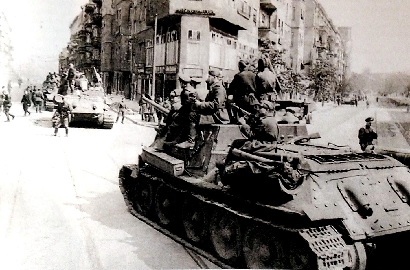 1945年5月，「苏德战争」期间，苏军的SU-100反坦克炮车正在德国一城市道路上驶过。此时德国已战败，但车上仍有一苏军士兵持枪警惕地注视着街道旁的高楼。