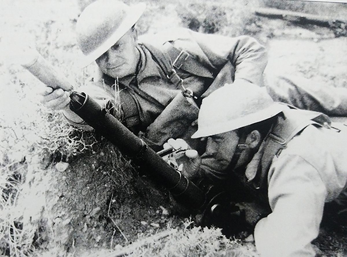 英军的2英寸迫击炮，一名士兵正在装弹，另一名士兵在调节发射角度。