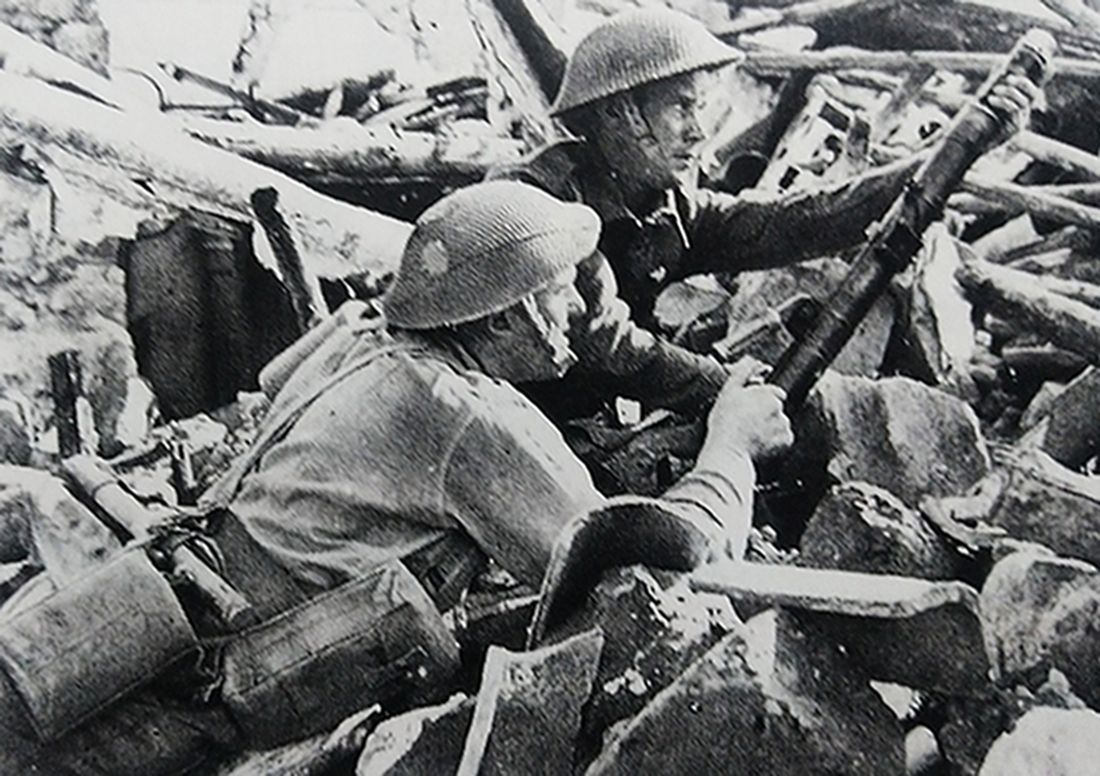 1943年10月，「意大利攻防战」期间，西线战场，意大利卡扎尼萨废墟中的英军士兵正为2英寸迫击炮装填炮弹，对敌方阵地进行炮击。