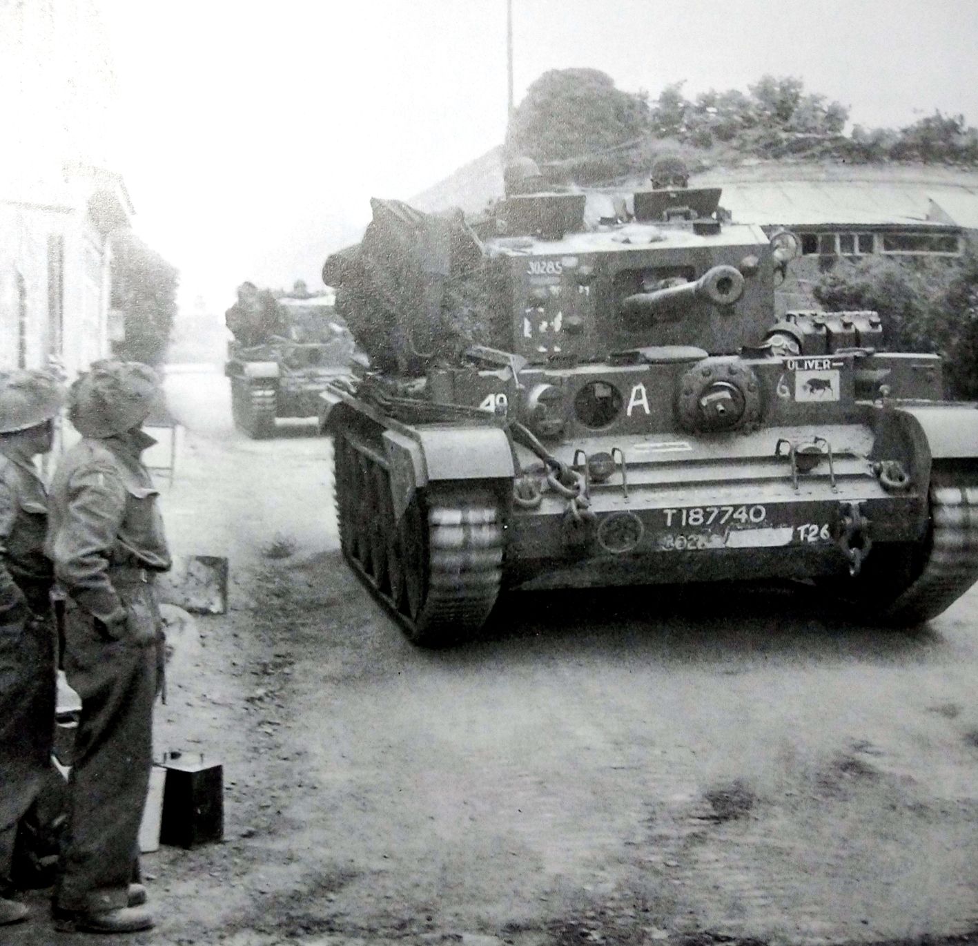 1944年6月,「诺曼底登陆」期间,法国诺曼底镇,一队英军「克伦威尔」巡航坦克正在行进。这辆编号为「T187740」的坦克印有英军第11装甲师的「公牛」标志。