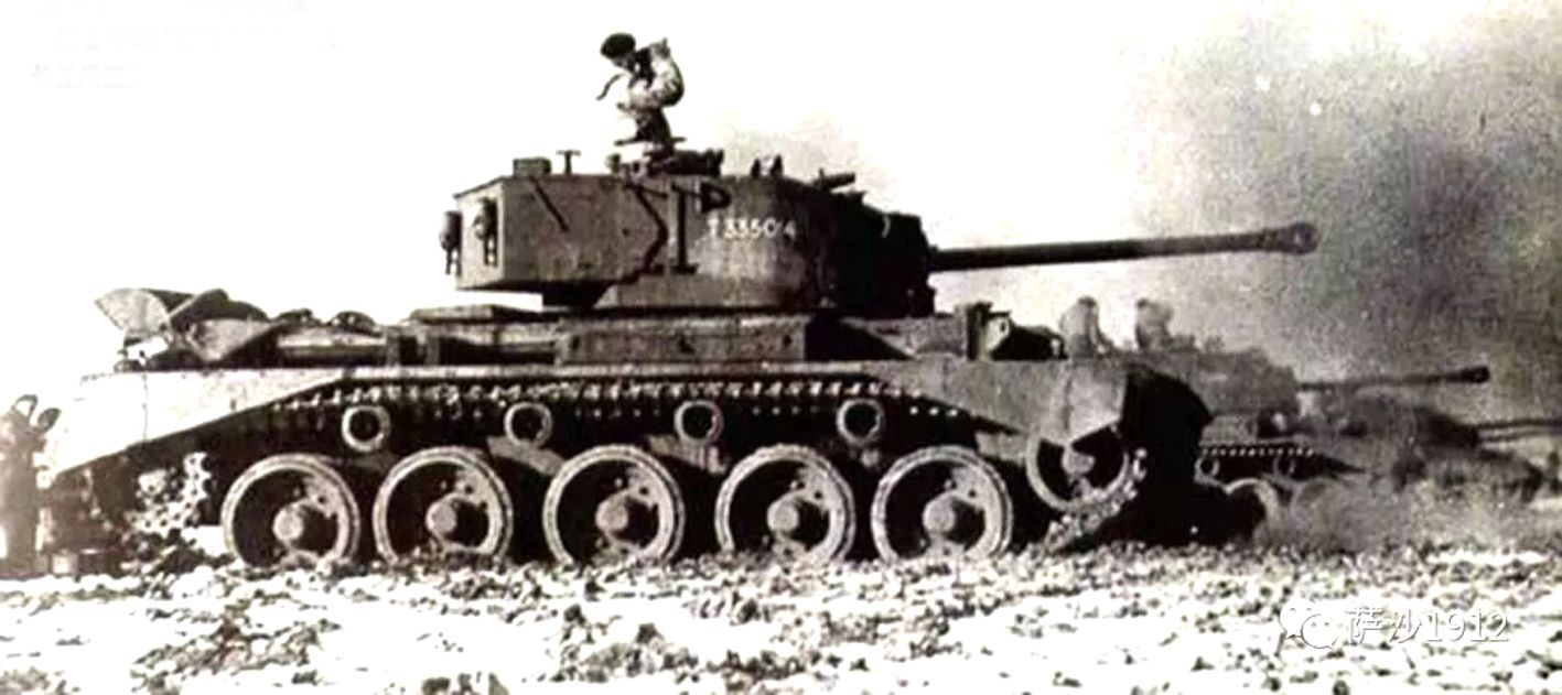 1945年欧洲战场,一队「慧星」巡航坦克正在向德军阵地进行射击,一辆坦克的车长正在用望远镜观察战果。
