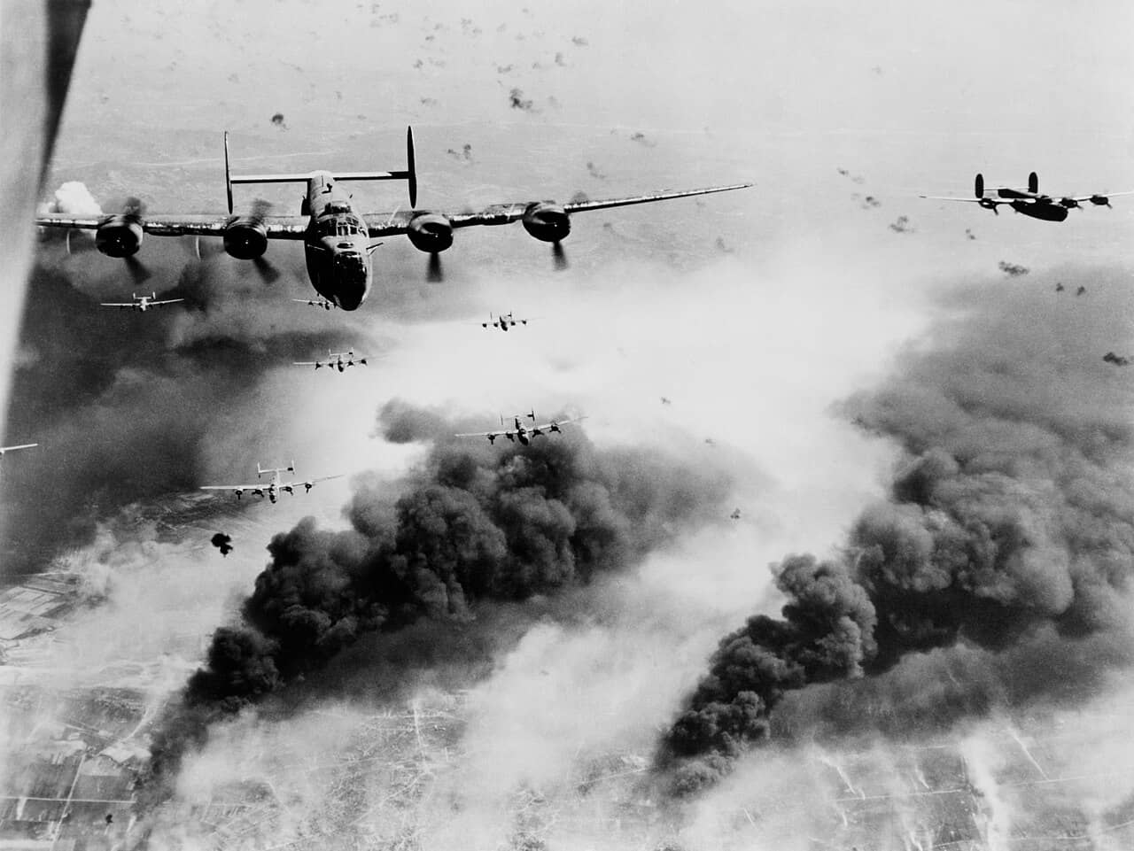 1944年5月31日,隶属于第15航空队的B-24轰炸机群飞越罗马尼亚普洛耶什蒂的康科迪亚-维加(Concordia Vega)炼油厂上空。它们在密集的防空炮火中穿行,下方则是先前几波轰炸机造成的破坏景象。
