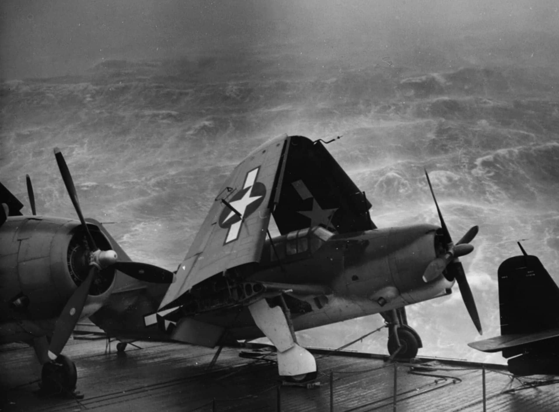 1944年,「夸贾林」号(USS Kwajalein,CVE-98)护航航空母舰在台风中航行,飞行甲板上的SB2C「地狱俯冲者」正做系留加固。