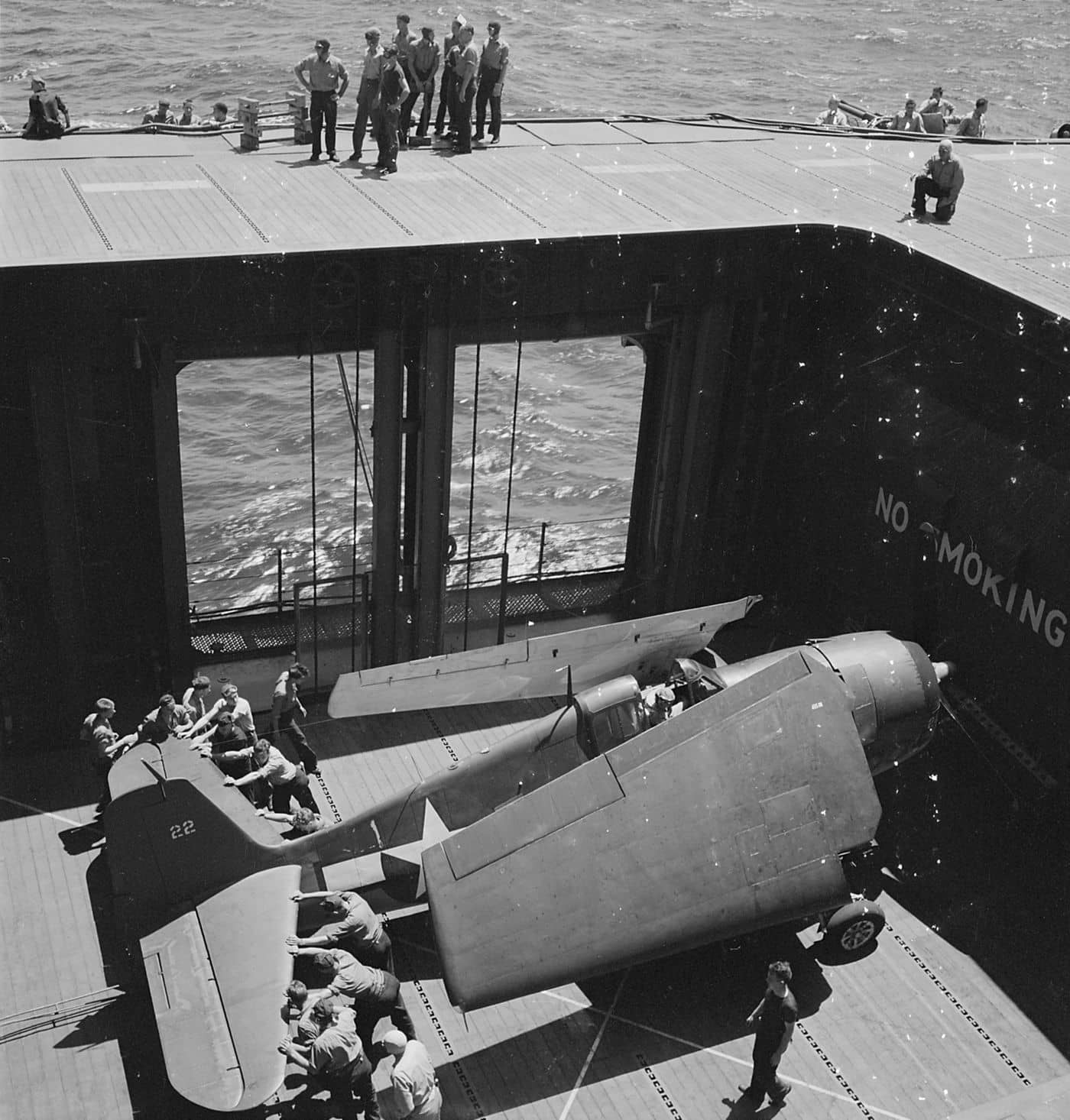 1944年6月,一架F6F「地狱猫」战斗机被推上「蒙特雷」号轻型航空母舰(CVL-26)的飞行甲板升降机。当月19日,「马里亚纳海战」爆发,美军舰载「地狱猫」在一天之内击落大量日军飞机,史称「马里亚纳猎火鸡大赛」,美军仅损失少量飞机便取得决定性胜利。注意其起落架舱外侧的机翼段绕着一个特殊取向的斜轴枢轴系统向后折叠,这是即格鲁曼公司拥有专利的「Sto-Wing」折叠机翼系统。