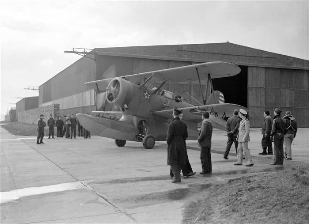 1942年初,苏格兰奥克尼群岛哈斯顿皇家海军航空站,一架美国海军 J2F「鸭」式水陆两用机正驶出机库,旁观的英美水兵为其让路。