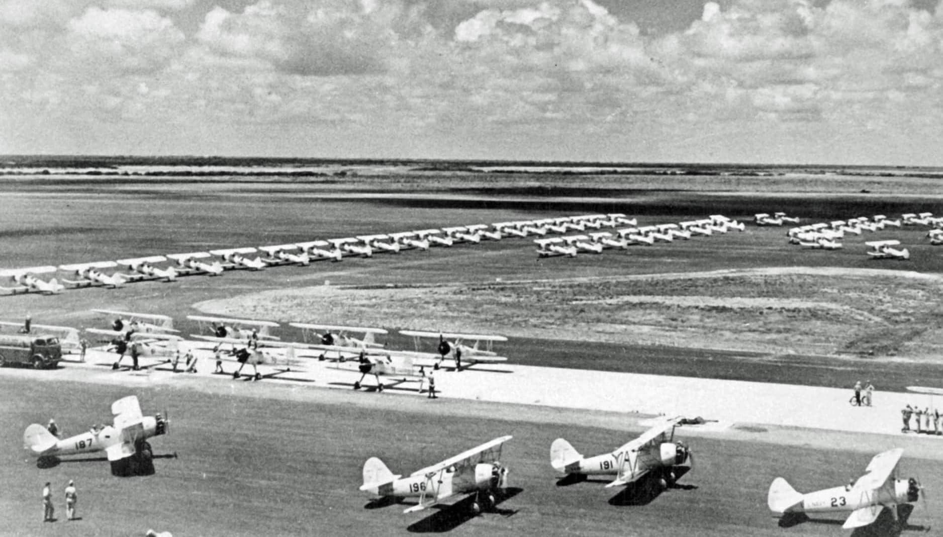 1942年，得克萨斯州科珀斯克里斯蒂海军航空站内排列的大批初级教练机。注：该基地是美国海军最大的初级飞行训练基地之一，画面以 N3N「金丝雀」为主、并混有 N2S 斯蒂尔曼教练机，展现了战时海军大规模扩训的场景。