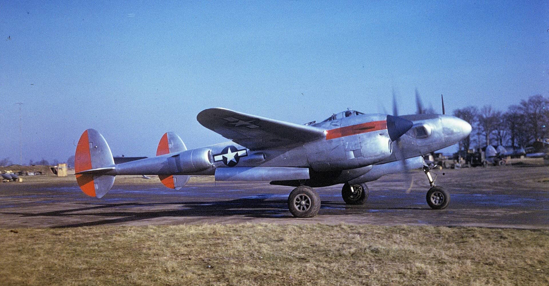 1944年,英国查尔格罗夫机场,一架隶属美国陆军航空队第7照相侦察大队、涂有识别色带的F-5「闪电」侦察机正在滑行道上滑行,其银灰色机身上可见美国陆军航空队机徽,醒目的红色识别带便于空中辨识友机。诺曼底登陆前,该大队曾以F-5低空拍摄海滩侦察照片,为「霸王行动」选点提供依据。