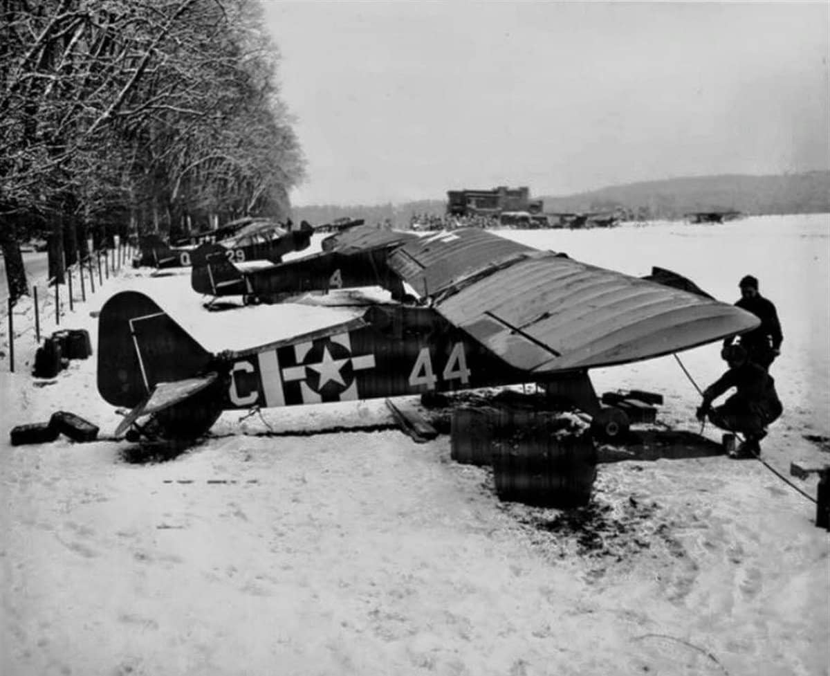 1944-1945年冬季,欧洲战场雪地简易机场上停放的「蚱蜢」机群,地勤人员正在机旁作业。L-4凭借短距起降能力可在最前线机场随部队展开。