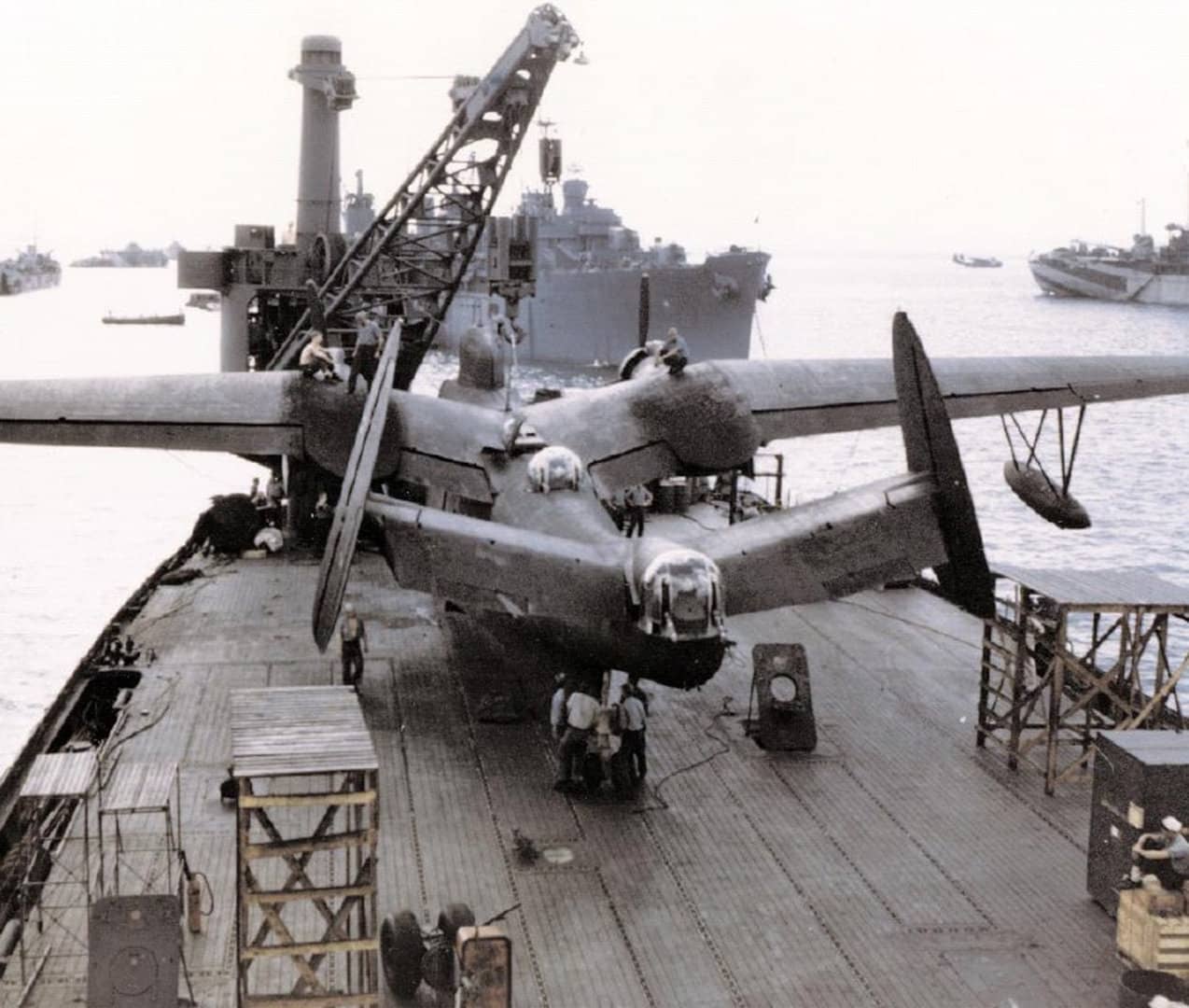 1945年4月，塞班岛塔纳帕格港（Tanapag Harbor），一架隶属于第26巡逻轰炸中队（VPB-26）的美国海军马丁PBM-5「水手」水上飞机被吊装到水上飞机母舰「诺顿湾」号（USS Norton Sound, AV-11）上。图片左侧背景中可见「LST-727」号坦克登陆舰；中央为潜艇母舰「富尔顿」号（USS Fulton, AS-11）；右侧为「肯尼斯·怀廷」号（USS Kenneth Whiting, AV-14），在其船尾后方的水面上还停着另一架PBM水上飞机。