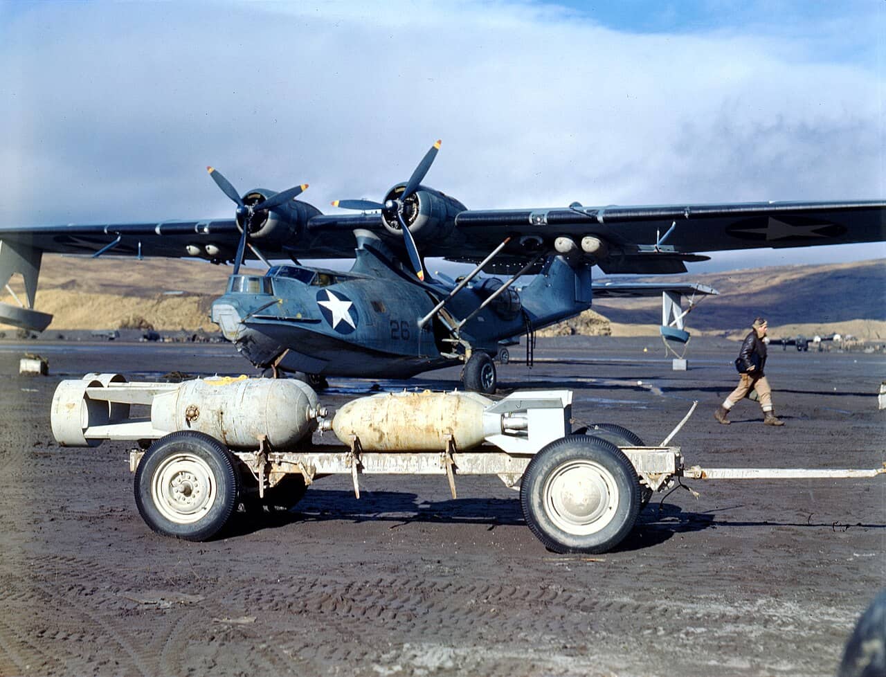 1943年，阿留申群岛阿达克（Adak），一架美国海军的联合PBY-5A「卡特琳娜」水上飞机正在装载深水炸弹和航空炸弹。注意背景中有一架废弃的联合B-24/PB4Y「解放者」轰炸机。