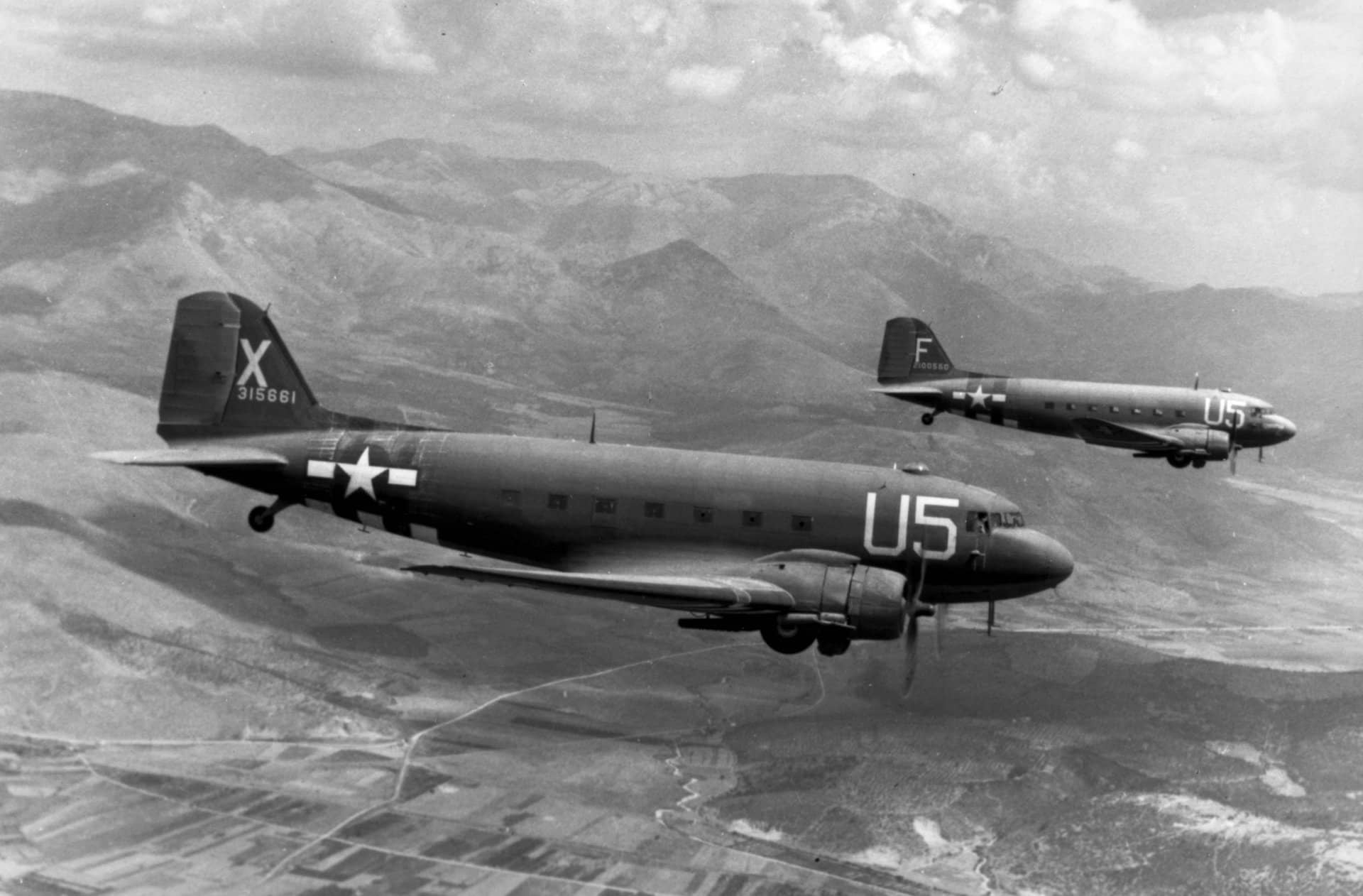 1944年8月15日,两架搭载伞兵、隶属于美国陆军航空队第12航空队第81运输中队的C-47A「空中列车」运输机正执行进攻法国南部的空降行动(行动代号「龙骑兵」)。后方那架飞机为道格拉斯C-47A-65-DL型(序列号:42-100550),镜头前方那架则为C-47A-90-DL型(序列号:43-15661)。