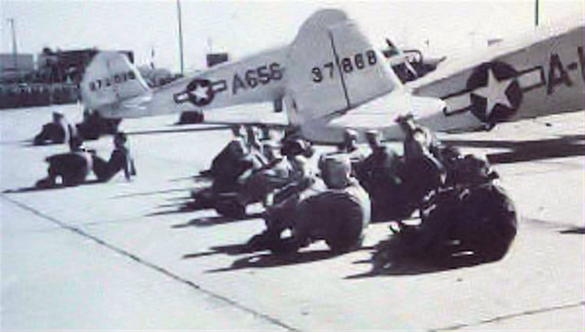1943年,亚利桑那州道格拉斯陆军机场的两架 UC-78C「山猫」运输机停放在停机坪上,前方一群地勤人员在休息。注:该基地为美国陆军航空队的双发高级飞行训练基地之一,UC-78 是标准教练与联络机型。