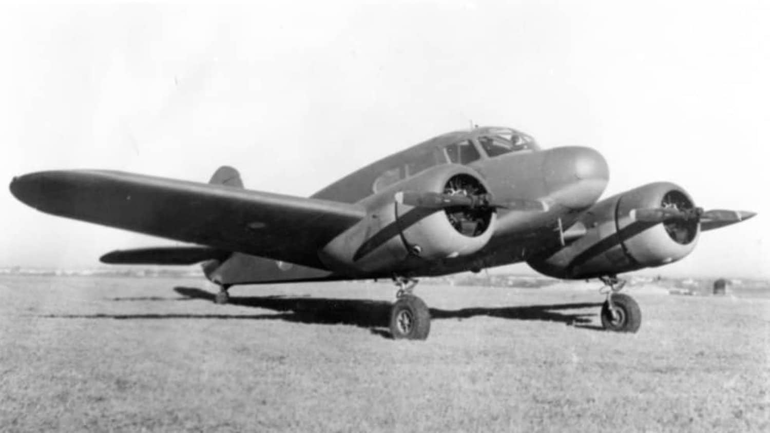 一架停在简易机场草坪上的美国陆军航空队 UC-78「山猫」运输机。
