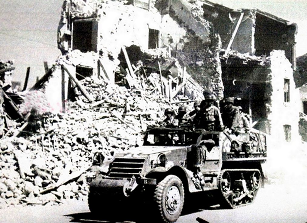 1943年,「西西里岛登陆战役」期间,一辆美军M3半履带装甲车穿过已成废墟的西西里岛上的一个村庄。这辆车隶属于布拉德里第2军总部。