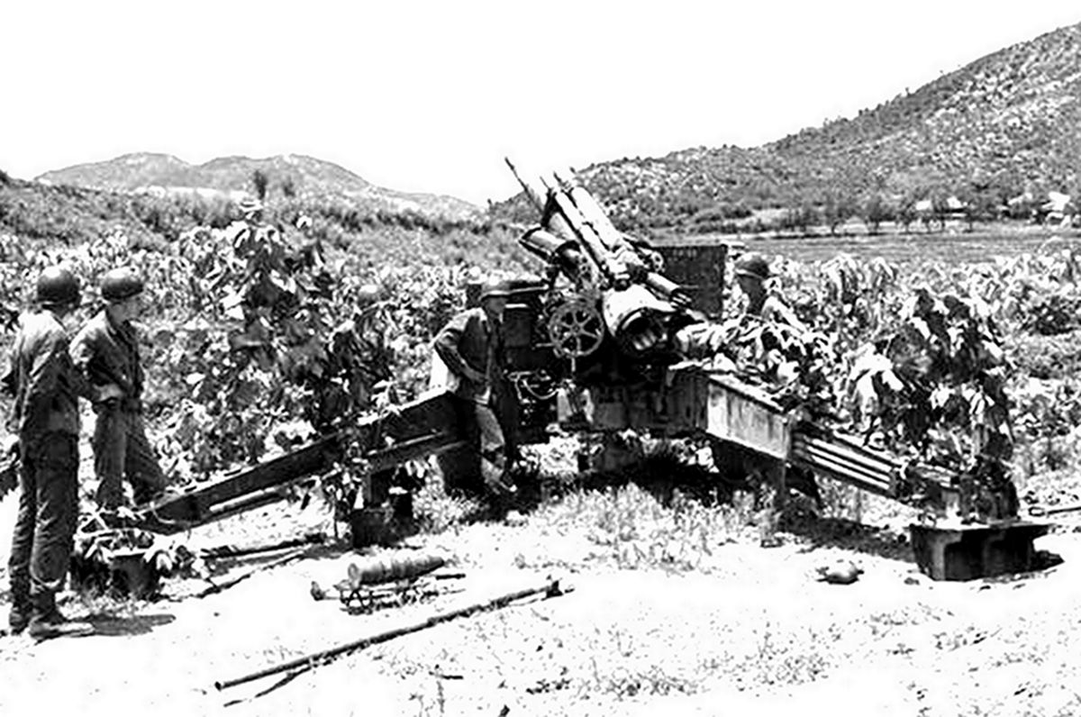 二战战场上，美军一门M1（M114）式155毫米榴弹炮的炮班士兵正在阵地上待命。