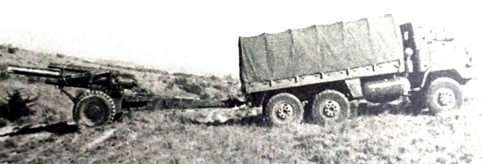 美军一辆6轮军车正牵引着一门M2（M101）式105毫米榴弹炮在山路上行进。