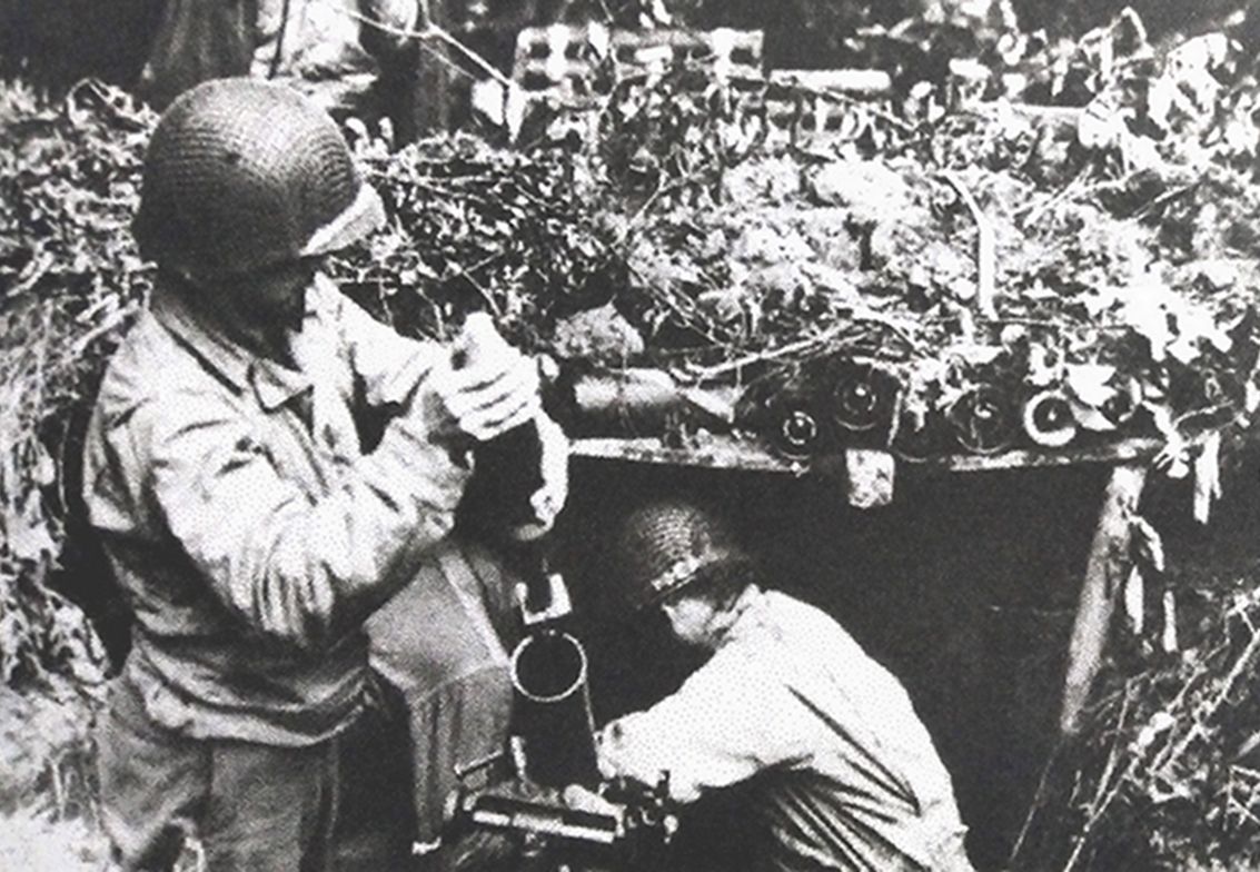 1944年夏，「诺曼底登陆」期间，西线法国诺曼底地区，掩体中的美军一门M1式81毫米迫击炮，一名士兵正准备向炮筒中放入高爆弹进行发射，为进攻的步兵提供火力支援。