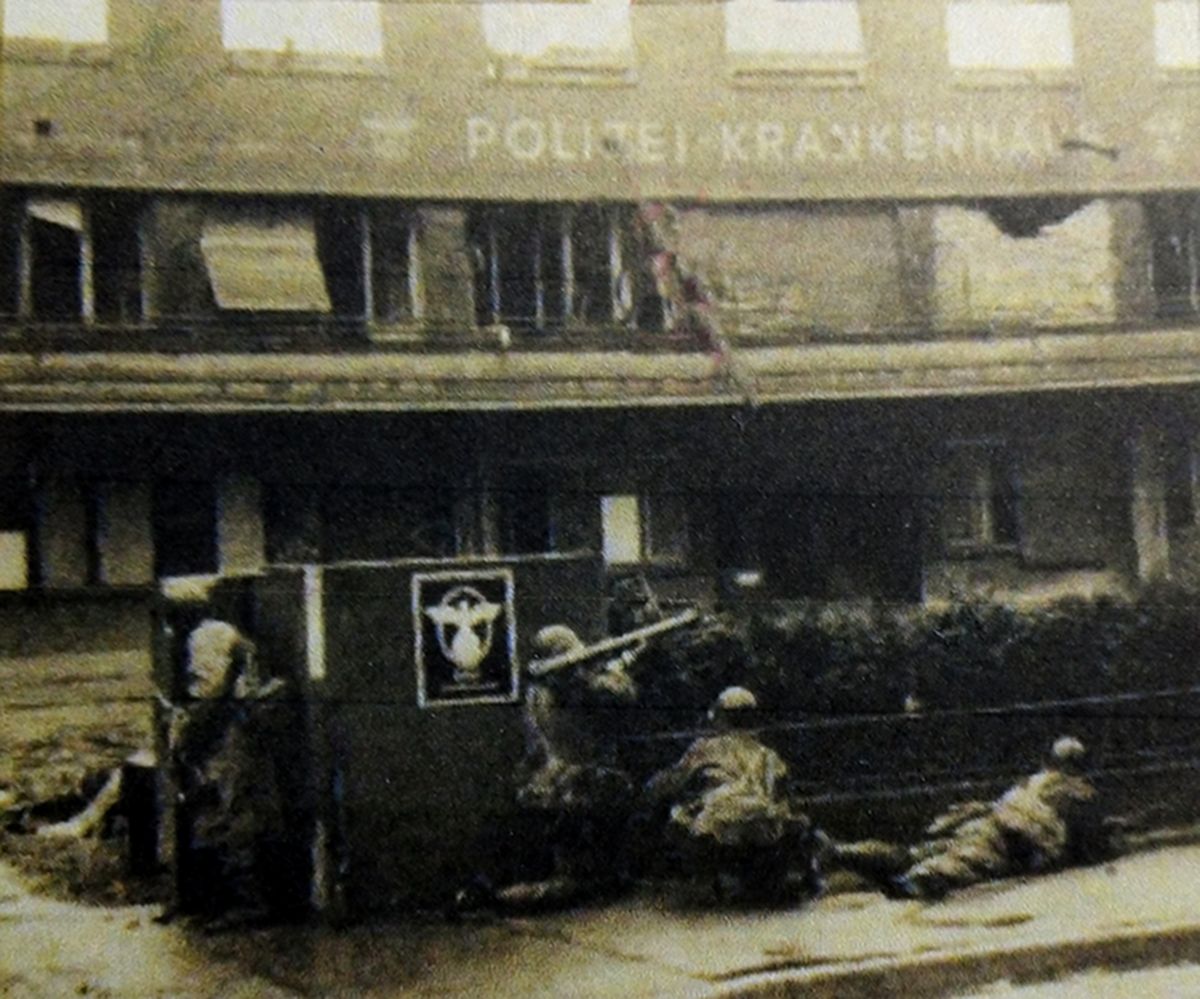 1945年3月，「莱茵河战役」期间，西线德国战场，由巴顿率领的美国第3集团军在奥本海姆附近渡过莱茵河后，在曼海姆车站附近作战的第94师一支步兵分队正在用M1A1型「巴祖卡」火箭发射筒攻击德军一个楼房工事。
