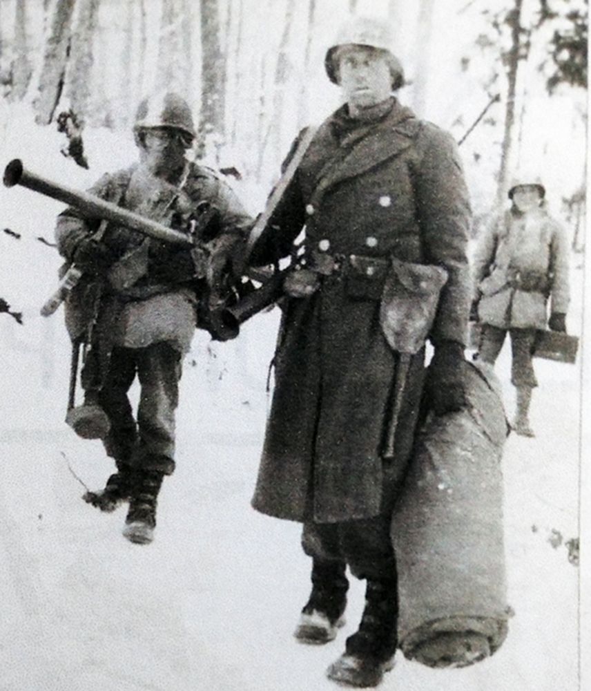1944年冬，西线战场，美军101工兵营B连一个火箭筒小分队的士兵背着M9A1型「巴祖卡」火箭发射筒行进在森林雪地中。