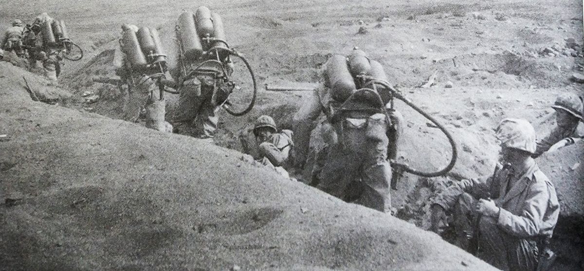 1945年初,「硫磺岛战役」期间,太平洋战场硫磺岛,美国海军陆战队一支火焰喷射分队正背着M2型火焰喷射器向前线运动。在太平洋战场的岛屿争夺战中,日军依托岛屿的复杂地形构筑了很多明碉暗堡,造成美军大量伤亡。在实战中,美军发现,用火焰喷射器摧毁这些碉堡和工事,杀伤躲在内部的日军,相对迫击炮和火箭筒效果会更好,因此,从1943年10月开始,美军为太平洋战区的每个师配备了更多的火焰喷射器,从过去的24具增加到60具。