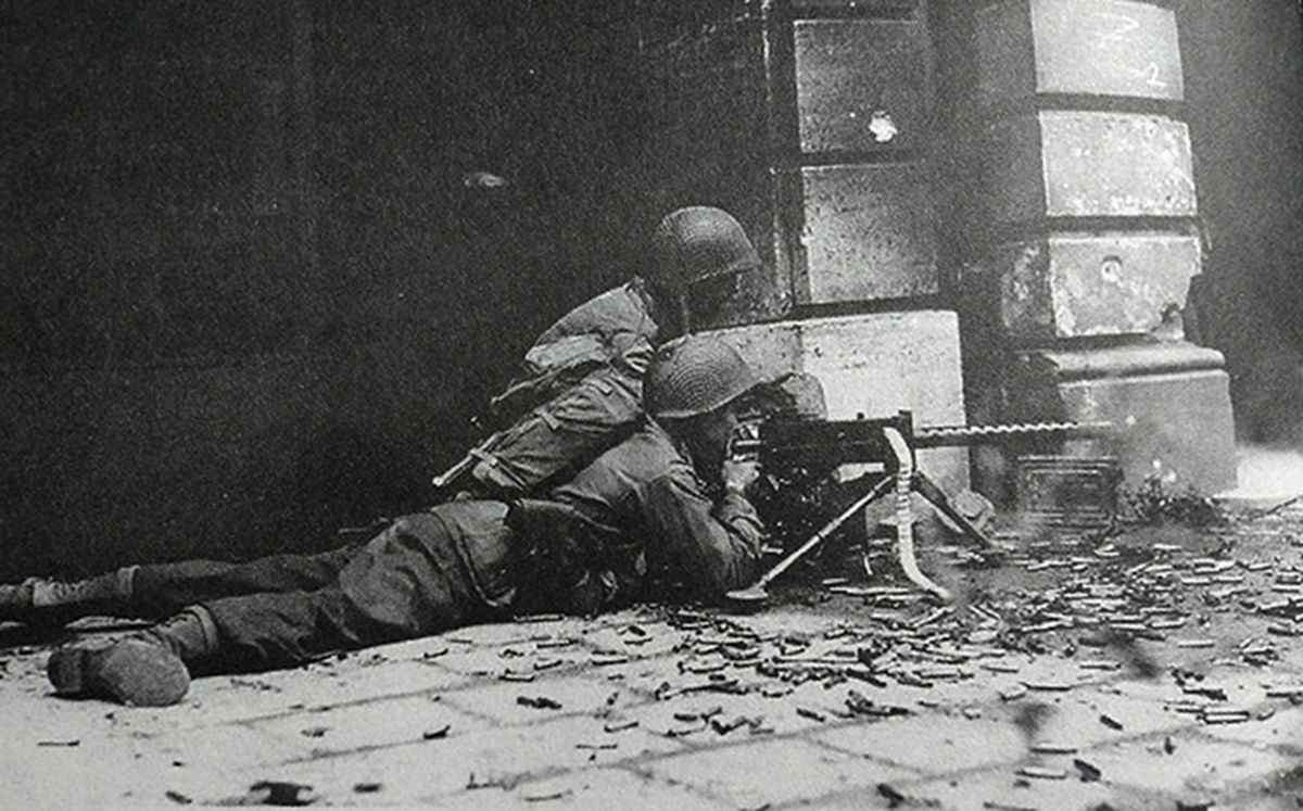 1944年10月，「亚琛战役」期间，西线德国战场亚琛街头，美军一个机枪小组正用一挺M1919A4重机枪向德军占据的建筑物射击。