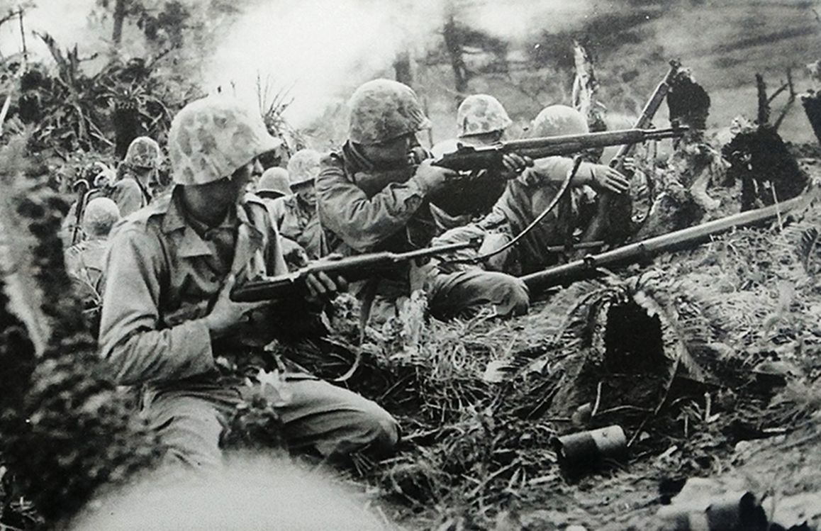 1945年4月，「冲绳岛战役」期间，太平洋战场，美国海军陆战队士兵与日军进行激烈交战。左前方一名士兵手持M1卡宾枪，中间一名士兵手持M1「加兰德」半自动步枪。
