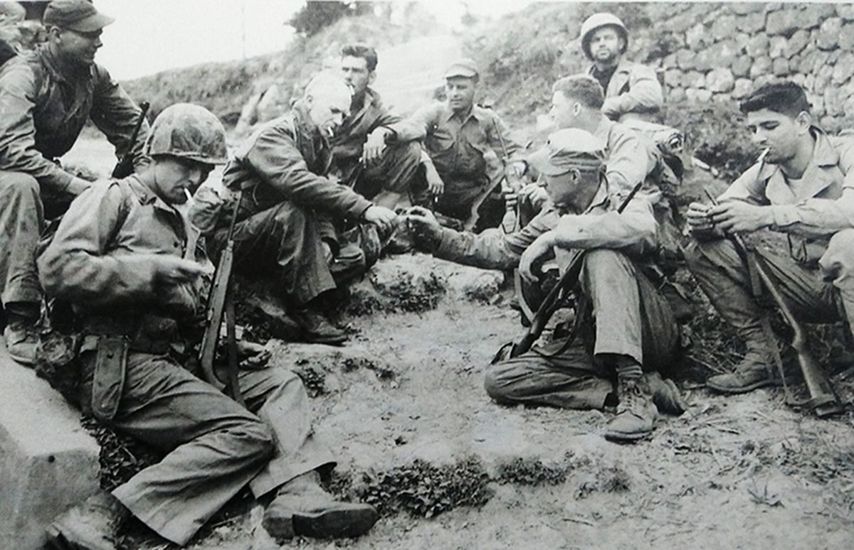 1945年4月，太平洋战场，美国著名战地记者厄尼·派尔（左起第3人）与一群美国海军陆战队员交谈抽烟，这些士兵大多配备了M1卡宾枪。