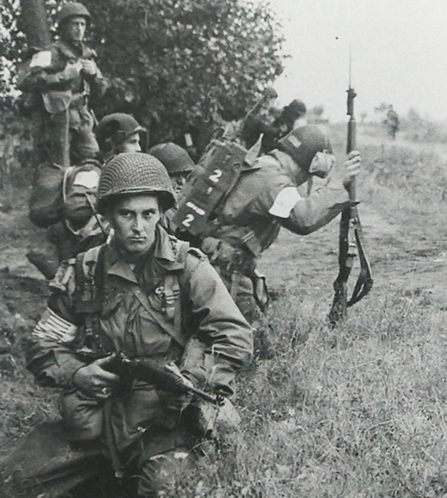 1944年9月，「市场花园行动」期间，西线荷兰，一支美国空降兵部队正停在路边警戒，前面一名士兵手持M1A1卡宾枪警惕地注视前方。在美军空降兵部队中，轻巧简便的折叠式M1A1卡宾枪很受士兵欢迎。