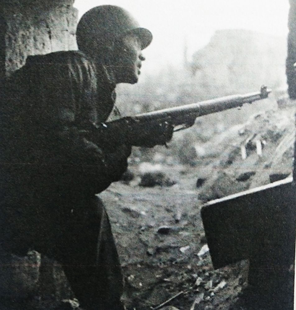 1945年2月，西线德国战场杜伦附近，美军第8步兵师一名手持M1「加兰德」半自动步枪的美军士兵正在躲避德军炮火，神情紧张。