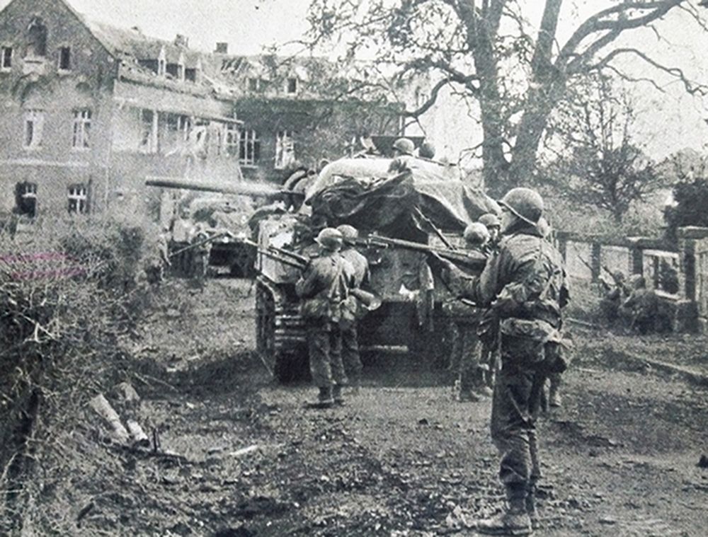 1944年11月，「鲁尔河战役」期间，西线战场德国，美军第84步兵师进攻盖伦基尔镇，英军第43步兵师出动谢尔曼坦克为美军步兵提供火力支援，图中手持M1「加兰德」半自动步枪的美军士兵正在坦克掩护下前进。