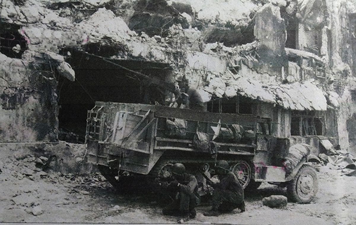 1944年9月,「帕劳战役」期间,太平洋战场卡罗琳群岛的帕劳,美军步兵在一辆M3半履带装甲车上的M2重机枪掩护下,准备对日军发起进攻,车旁是已被战火摧毁的楼房。