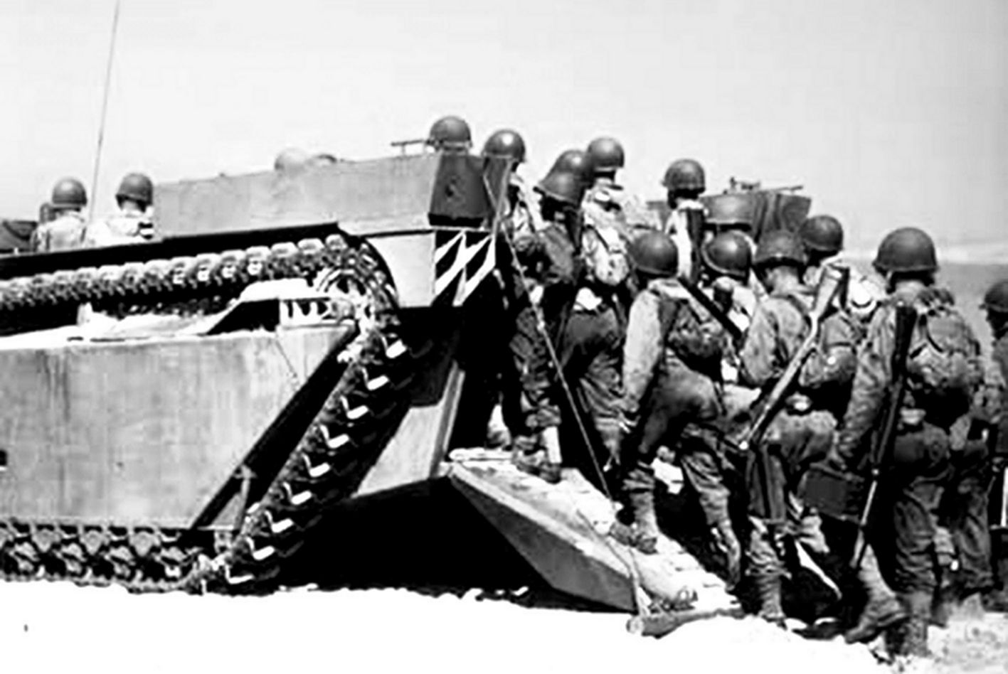 1945年，「冲绳岛战役」期间，美军战士陆续从打开的尾板登上LVT3两栖装甲车。